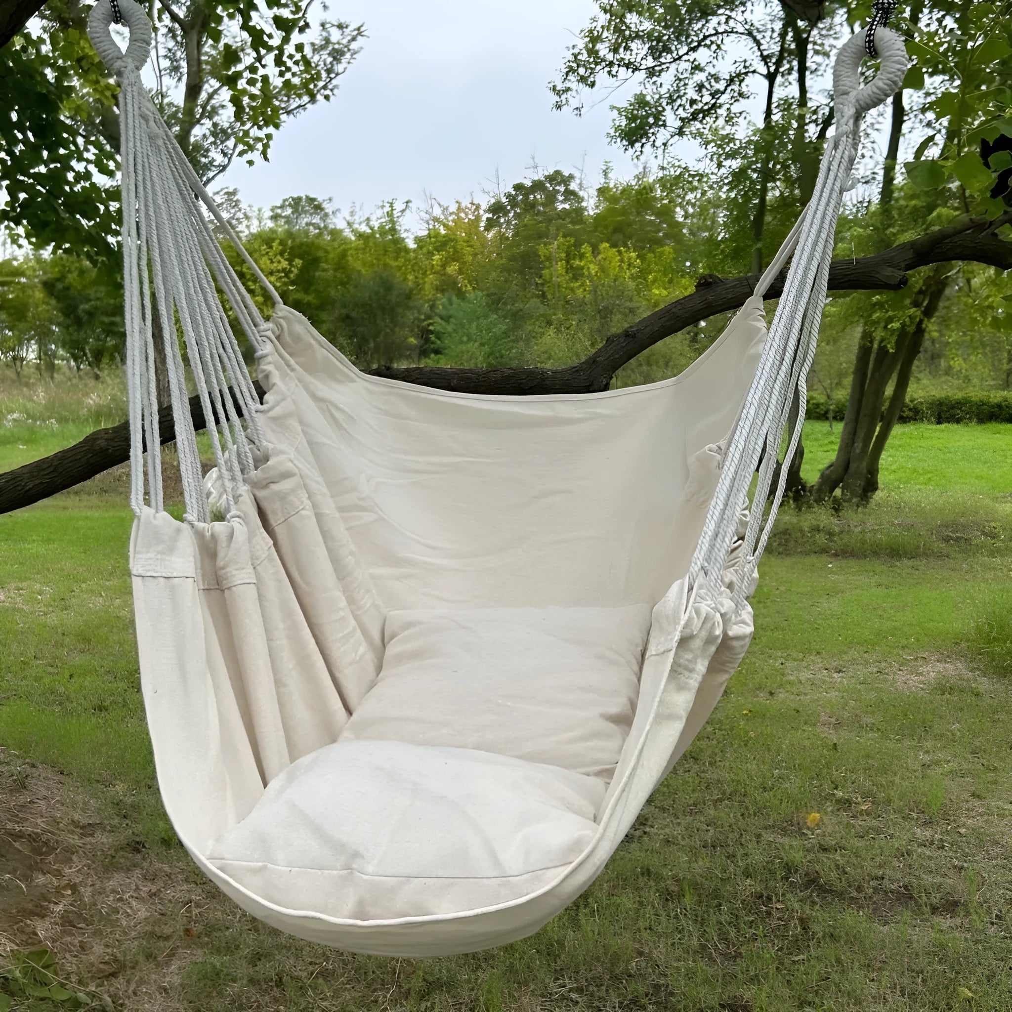 Folding canvas hammock in beige with seat cushion and three-section iron pipe on a garden background