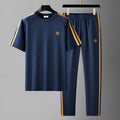 Man wearing a blue short sleeve polyester tracksuit set, showing the matching top and trousers.