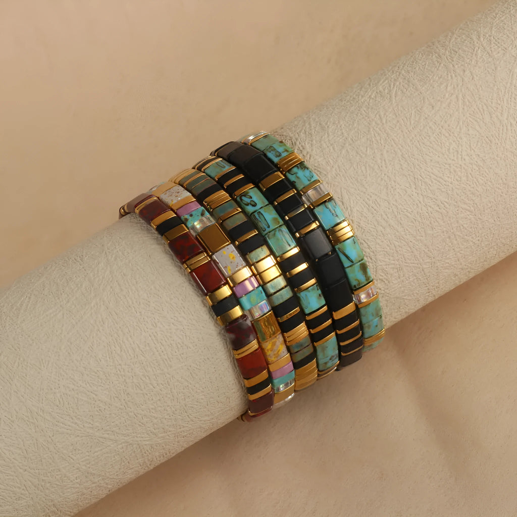 Geometric glass beaded bracelet in milky white, black, green, blue, or red on a plain background.