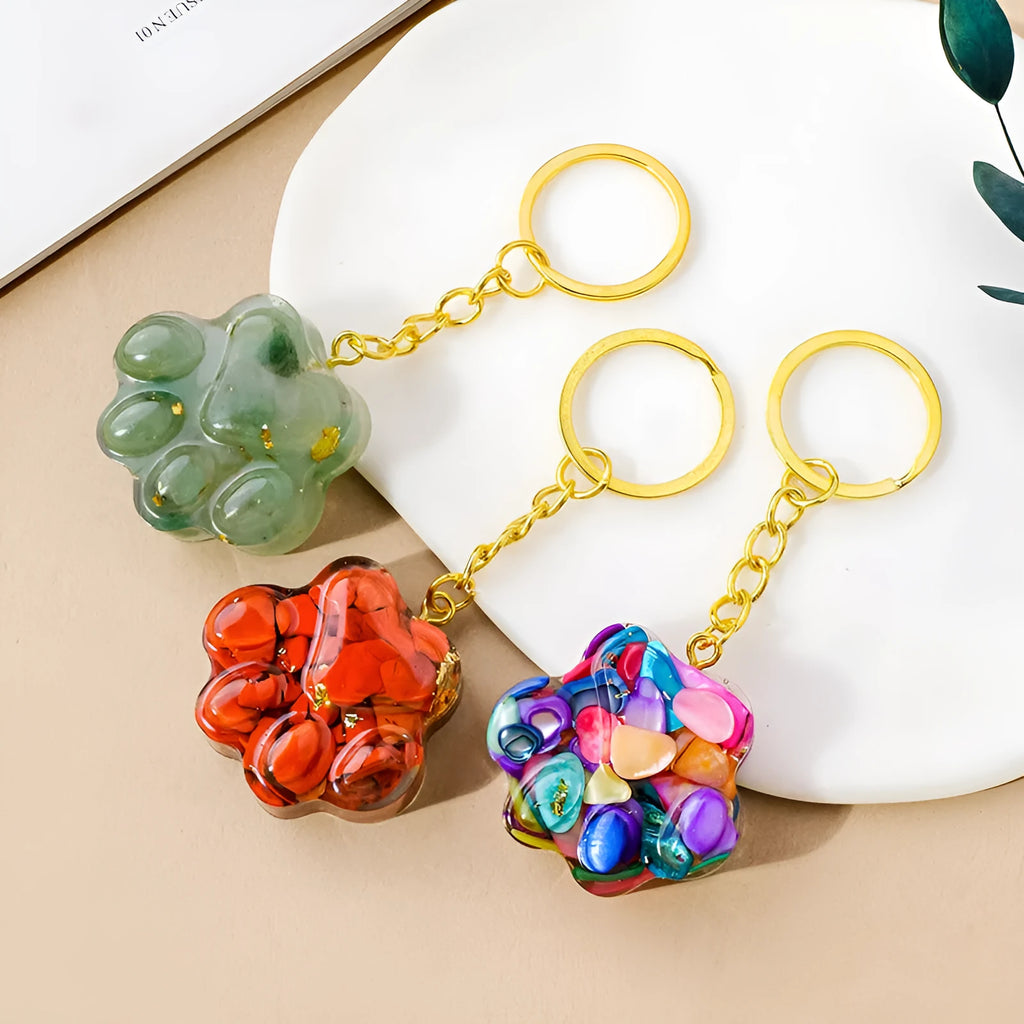 Small natural crystal cat's paw shaped pendant on a keychain ring, shown in various crystal colour options.