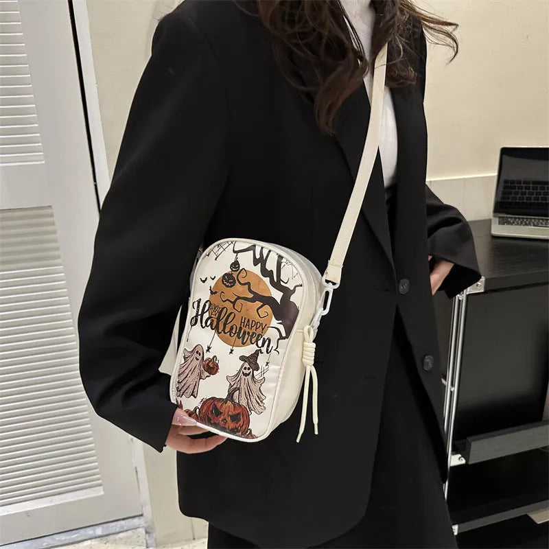 Black mini crossbody bag with Halloween graffiti print of cartoon pumpkins and bats.