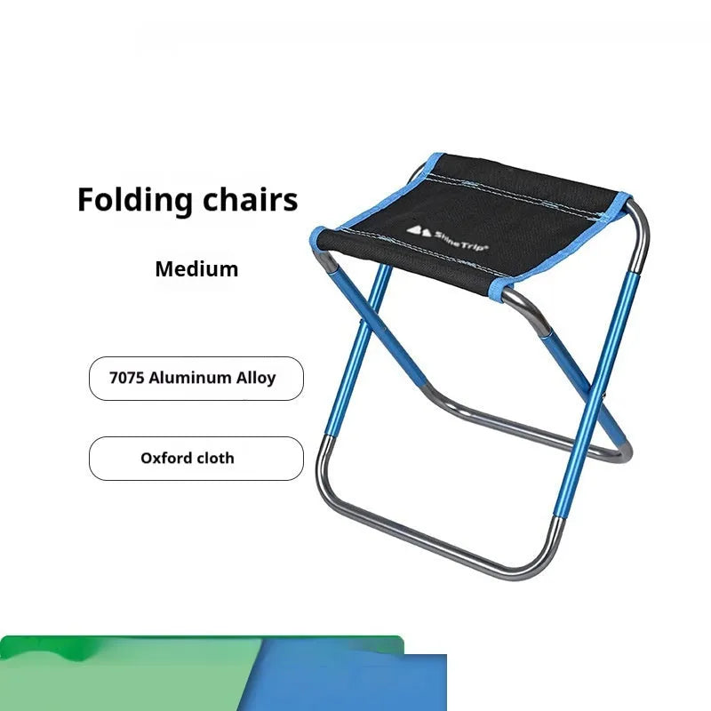Black ethnic style aluminium alloy folding stool set up on grass.
