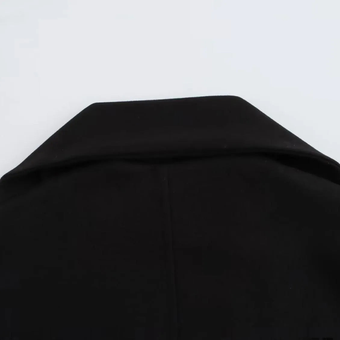 Woman wearing a long black overcoat with a detachable artificial fur collar, styled in a street-fashion look.