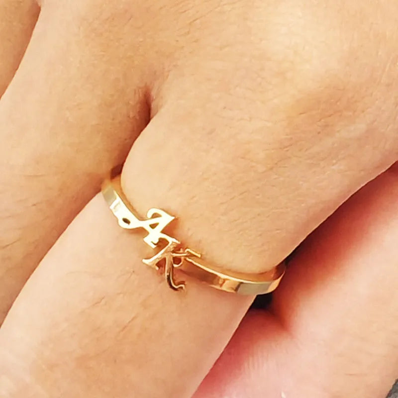 Customised 2 letters open ring in stainless steel with gold electroplated finish on a plain background