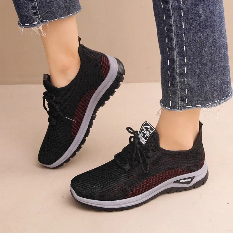 Women's black casual sneakers with mesh upper, cross straps, and round toe on a rubber sole.