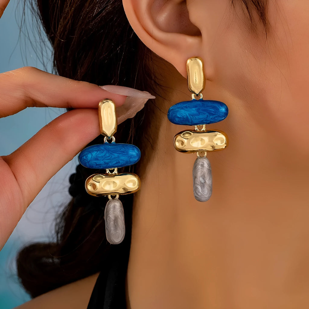 A pair of geometric multicolour stud earrings for women on a plain background.