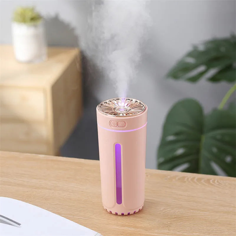 Black and white portable USB rechargeable car humidifier with colourful LED lights on a desk.
