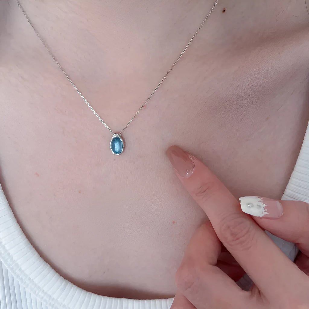 Geometric navy blue water drop pendant on an adjustable copper cross necklace for women.