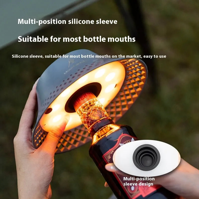 Beige and grey wine bottle-shaped camping lantern with USB-C port on a wooden table.