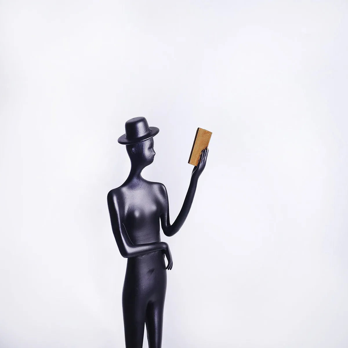 Black cast aluminium desktop sculpture of reading woman measuring 12x12x51cm
