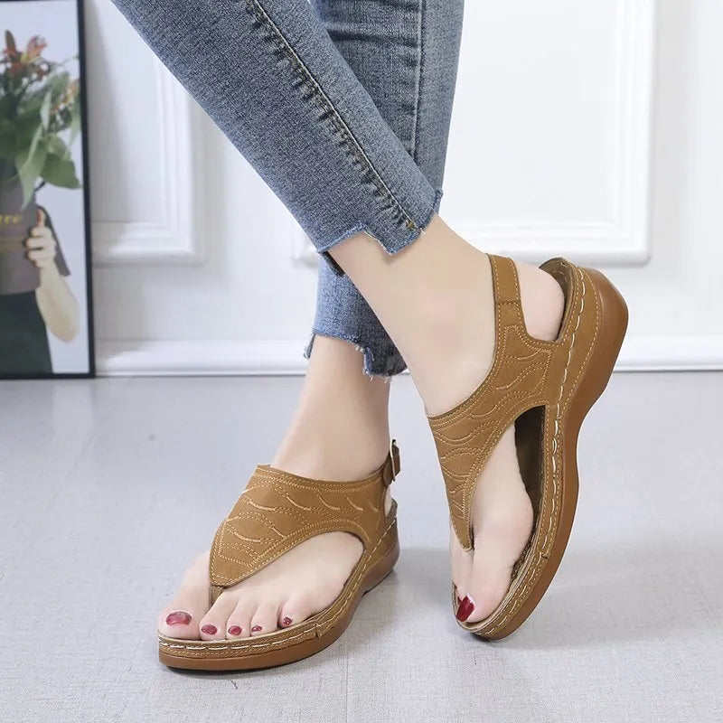 Women's red wedge heel sandals with an adjustable buckle strap on a plain background.