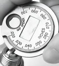 Round zinc alloy spark plug gauge with dual scales on a white background