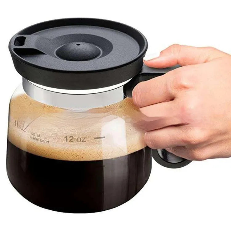 Transparent borosilicate glass coffee maker with black silicone cover on a stovetop