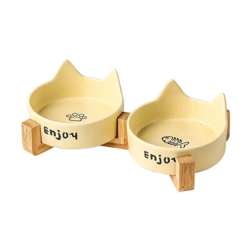 Porcelain cat bowl with cat ear handles in a wooden anti-tumble frame, showing paw print design.