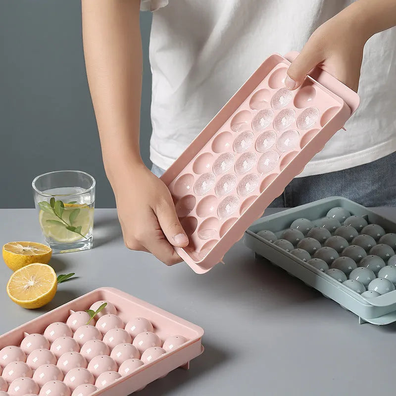 Sky blue and pink 3D round ice cube mould trays showing spherical cavities.