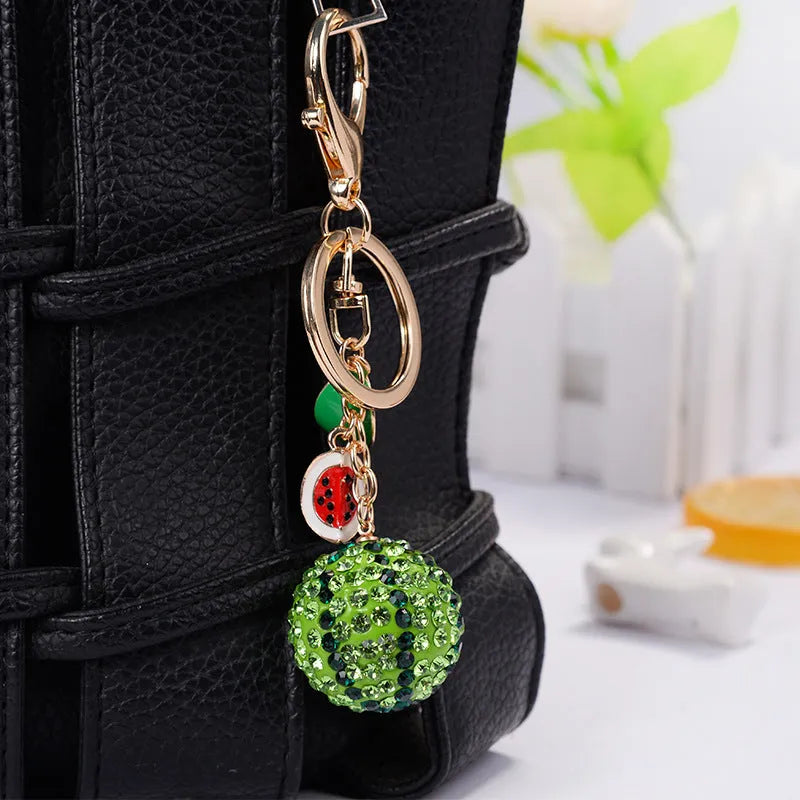 Green zinc alloy watermelon keychain on a key ring, showing detailed fruit shape.