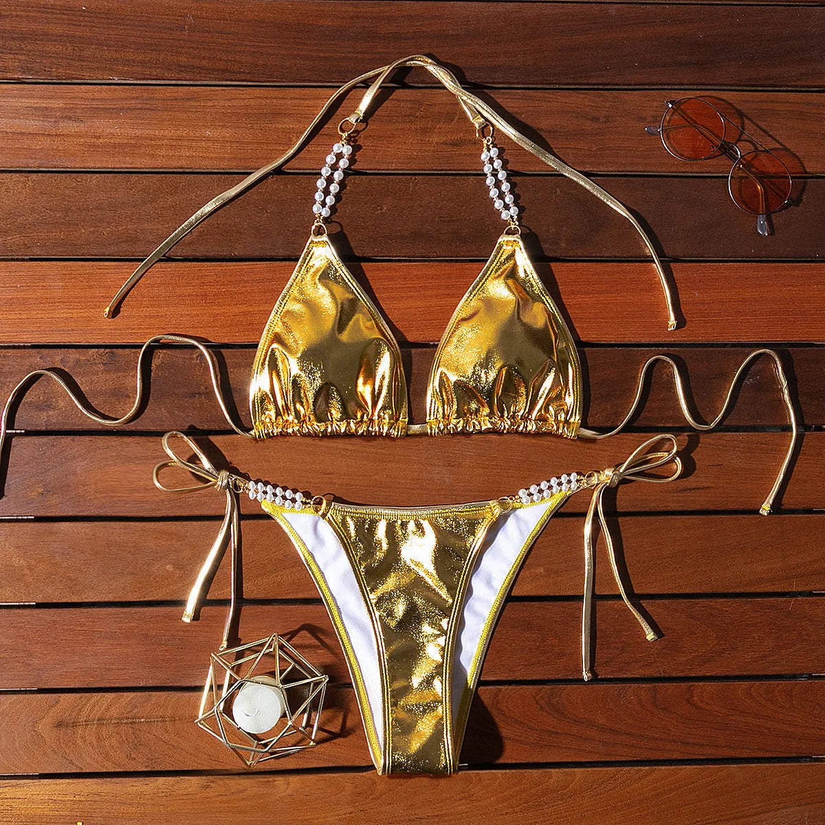Gold bronzing effect women's halter neck bikini with lace-up back and pearl chain detail on mannequin