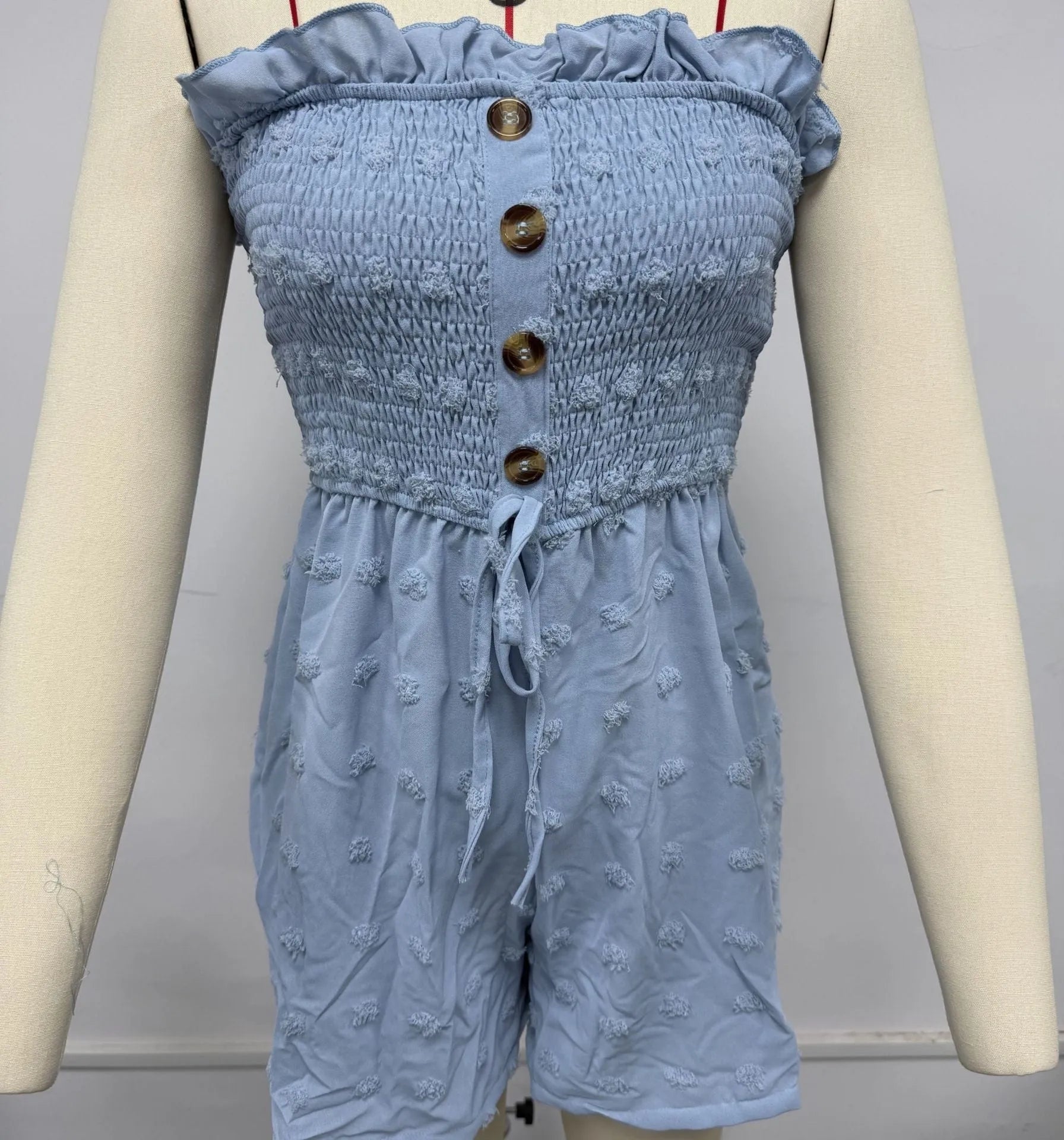 Solid colour off-shoulder sleeveless women's jumpsuit on a hanger, showing button detail and mid-waist design.