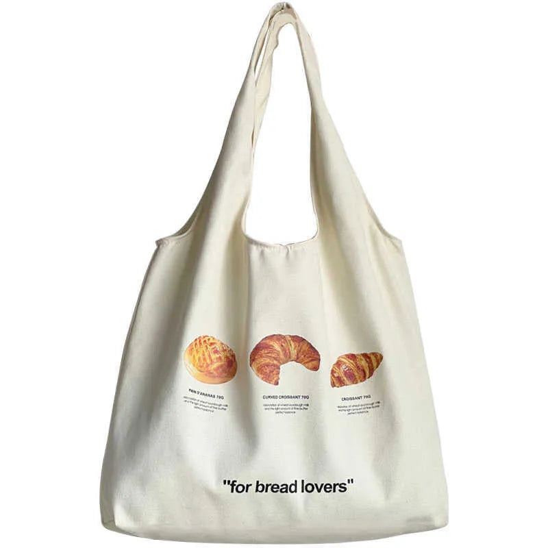 Beige canvas bag with bread patterns including croissant design, showing one-shoulder strap and structured form