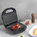 Black electric sandwich pan with brushed stainless steel top cover showing non-stick cooking surface