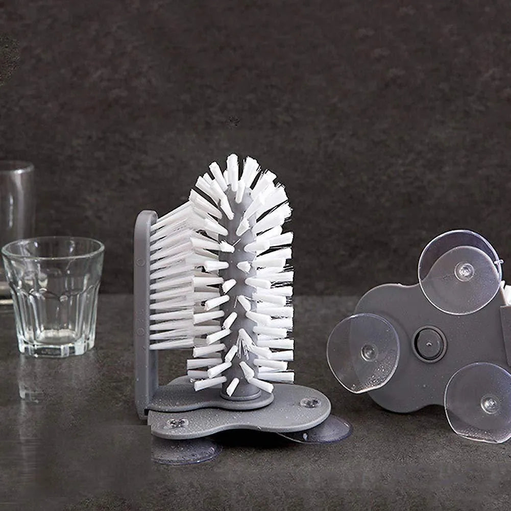 Grey 2-in-1 cup scrubber with double-sided bristles and three suction cups on a white surface