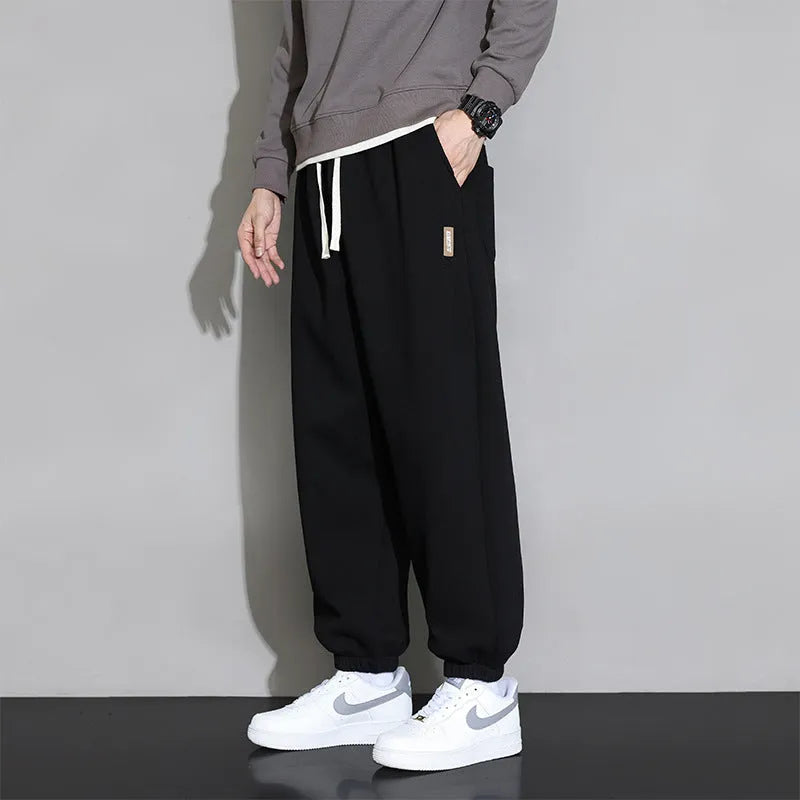 Men's loose grey casual sports trousers with drawstring waist on a plain background