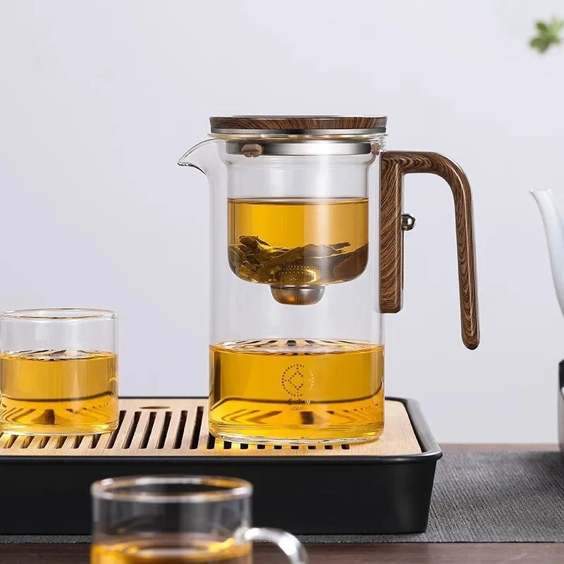 Glass teapot with wooden handle showing magnetic separation button and inner filter basket.