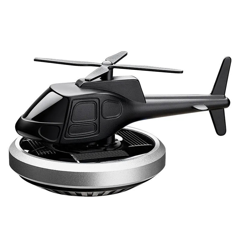 Silver metal solar-powered rotating helicopter car air freshener ornament on a dashboard.