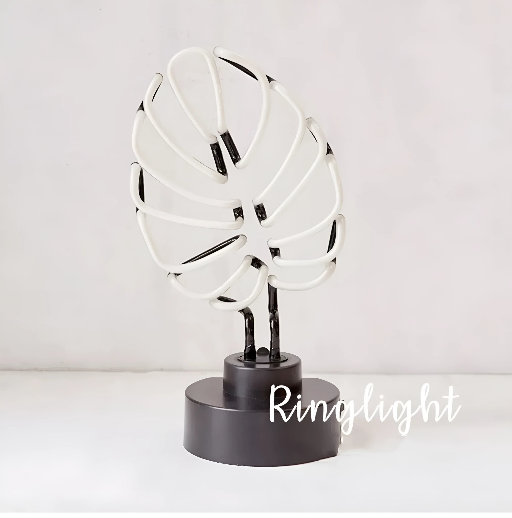 Minimalist white bamboo-shaped desk lamp emitting a soft green light, shown on a table.