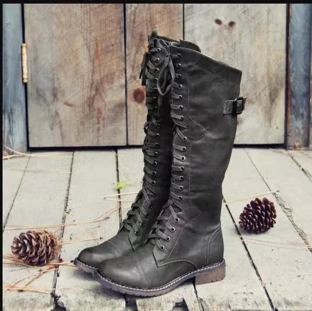 Women's black high-leg boots with a round toe and a low chunky rubber heel on a white background.