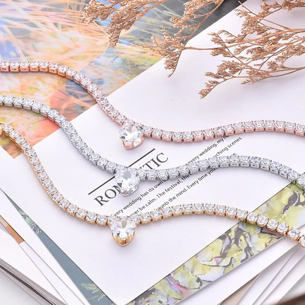 Gold heart-shaped rhinestone dog collar on a white background, showing shiny crystals and adjustable clasp.