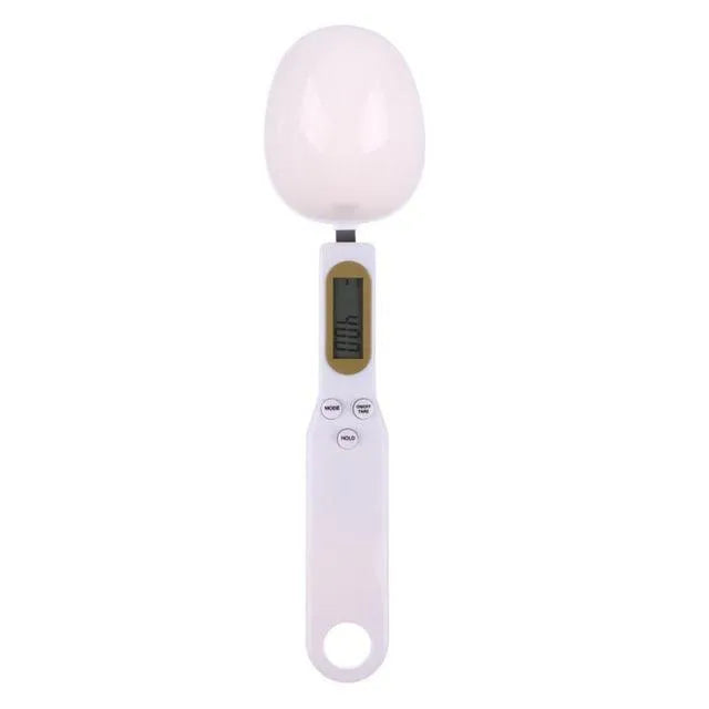 White electronic digital spoon scale with LCD display on a kitchen counter.