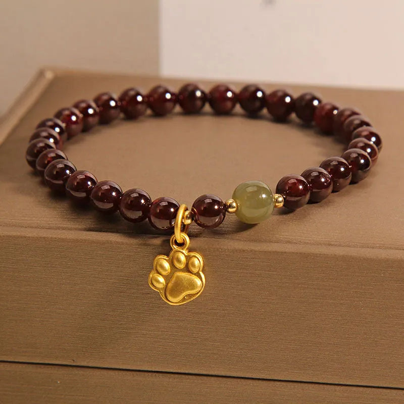 Women's crystal bracelet with a cat's paw garnet design on a polished metal setting.