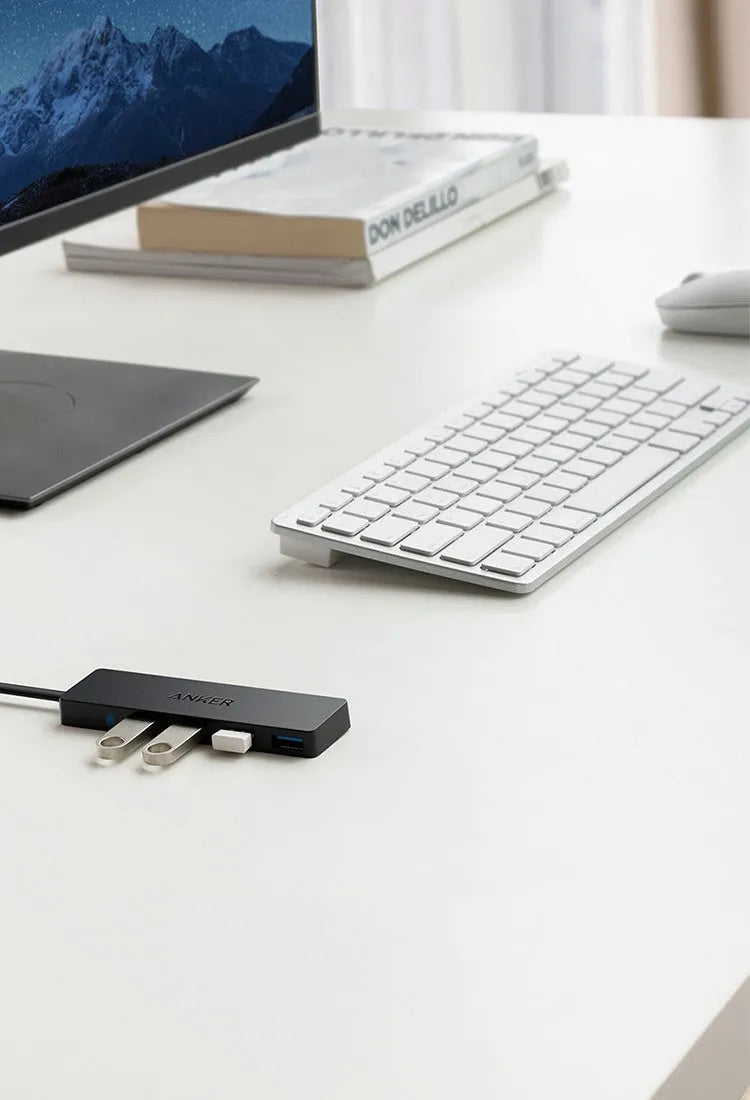 Black Anker 4-port USB 3.0 hub with short attached cable on a desk.