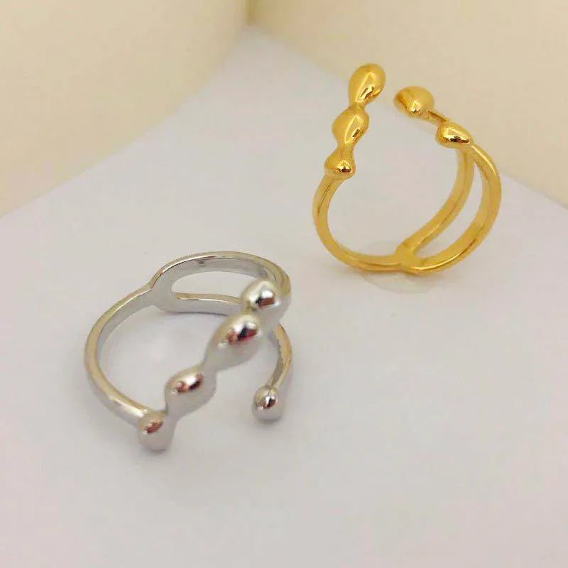 Gold and silver adjustable opening fashion ring with spherical design on a brass base.