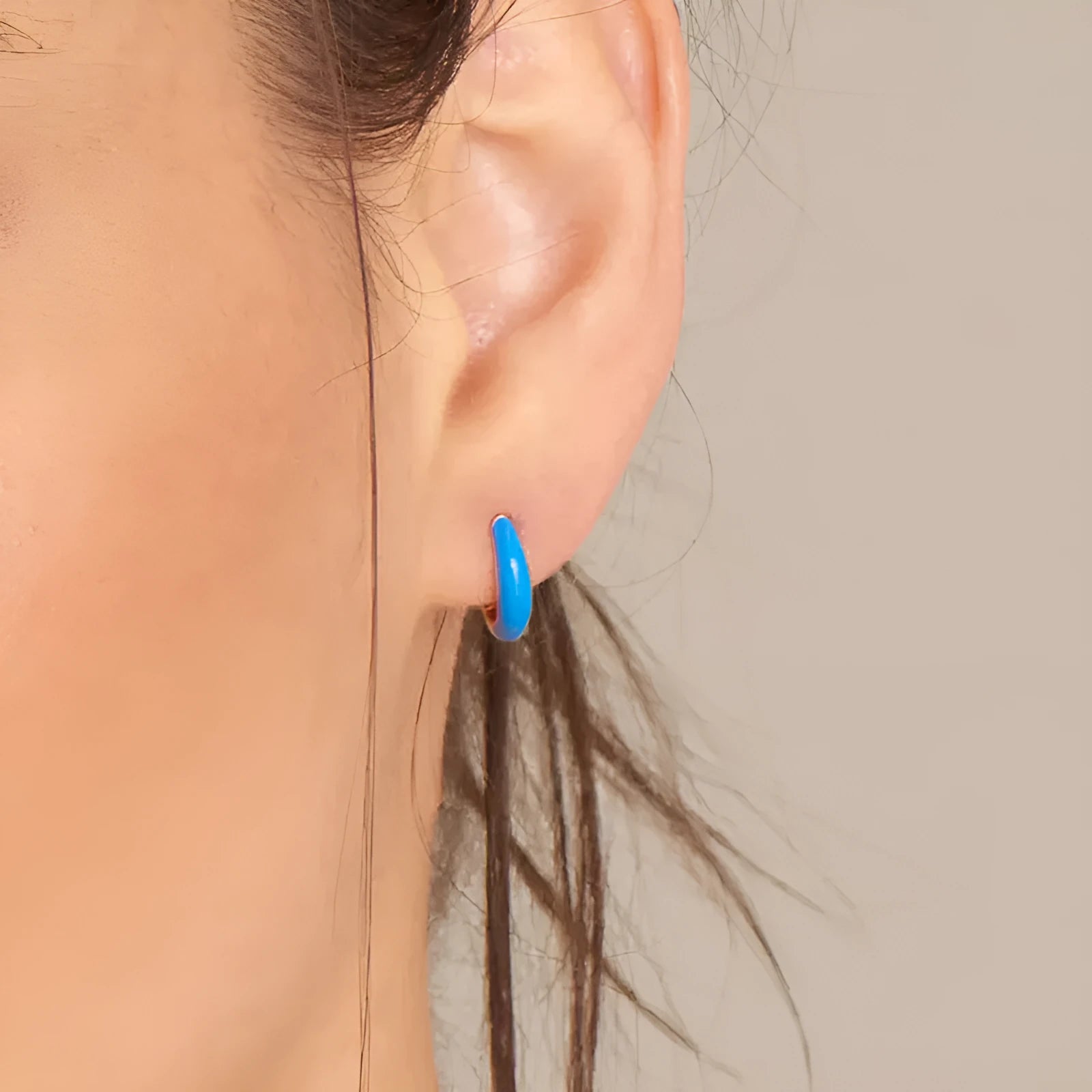 A pair of oval curved epoxy earrings in various colours with geometric ring details on a silver needle copper frame.