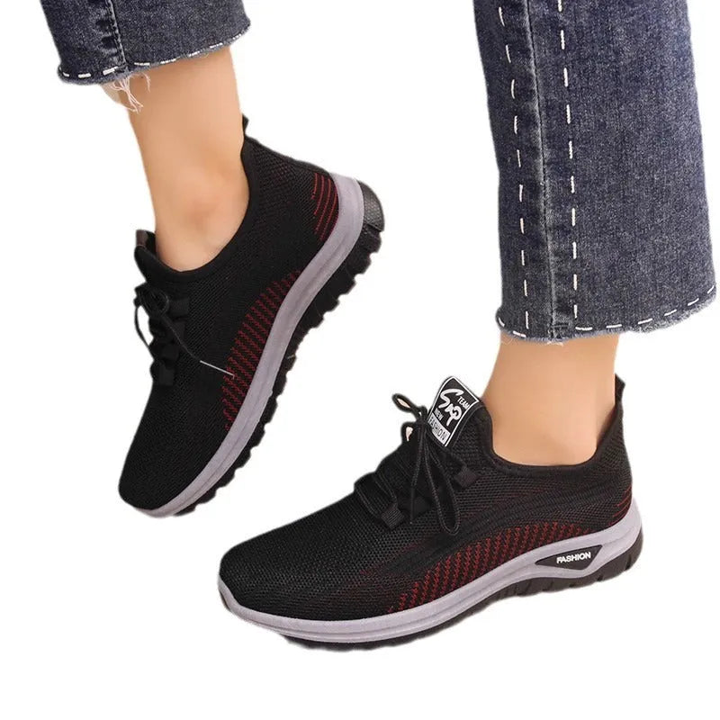 Women's black casual sneakers with mesh upper, cross straps, and round toe on a rubber sole.