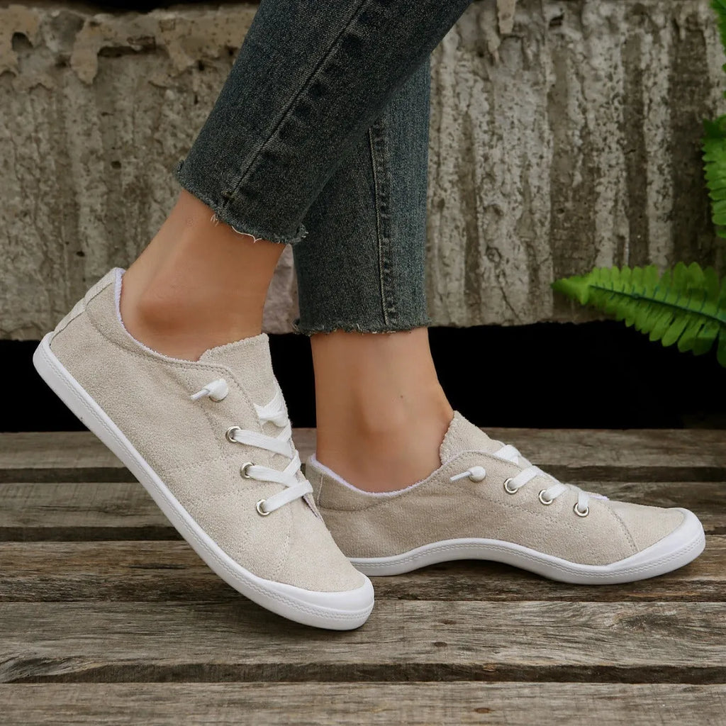 Women's creamy white low-top fabric casual sneakers with a rubber sole on a neutral background.