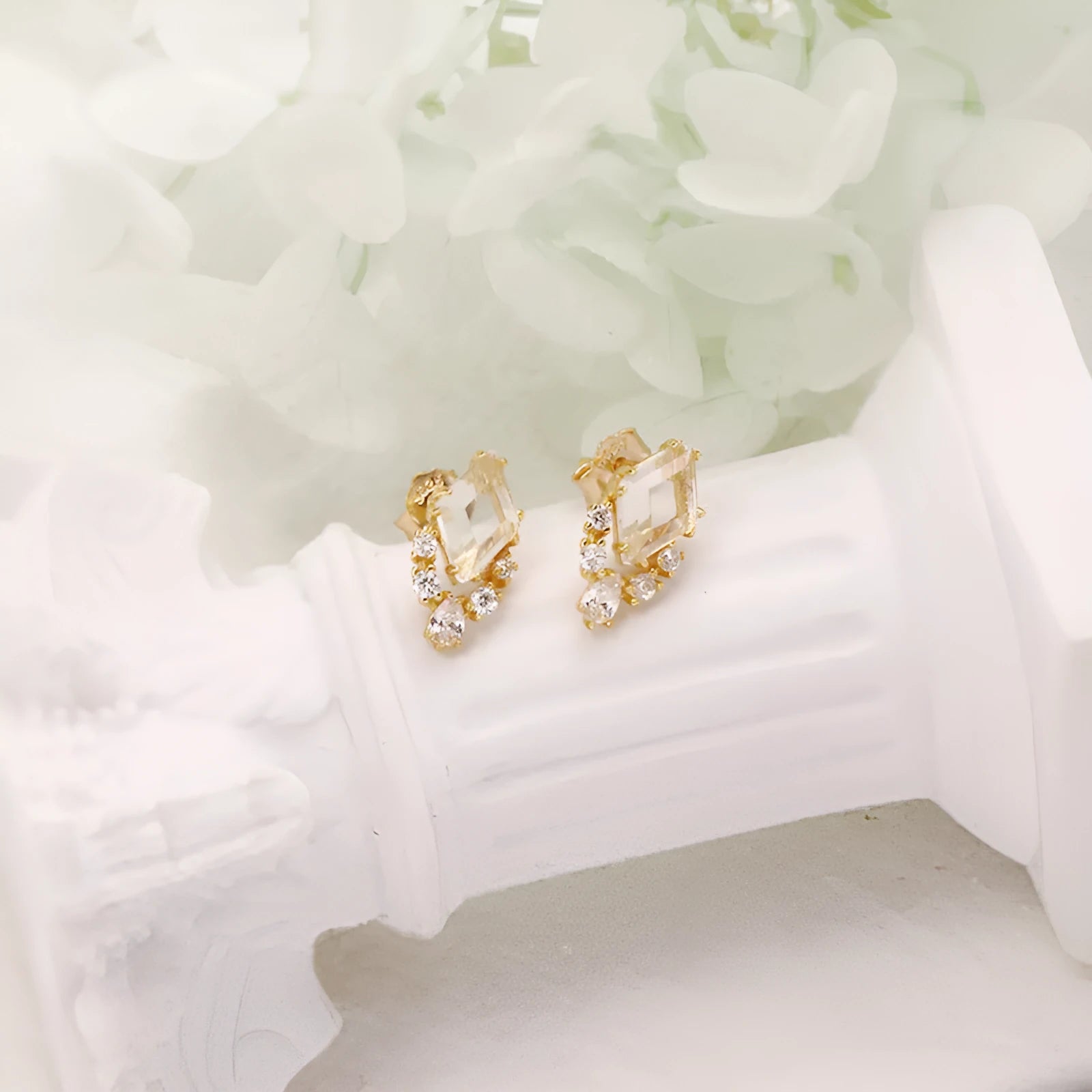 A pair of geometric sterling silver earrings with sweet white crystal studs on a white background.
