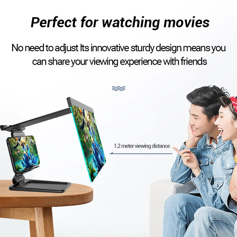 Black detachable mobile phone screen amplifier and folding holder shown on a desk next to a phone.