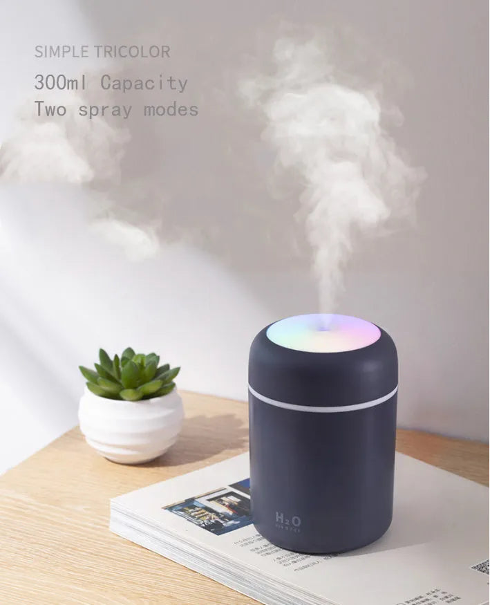 Mini ultrasonic essential oil diffuser with 300ml water tank in white, showing coloured night lights and USB cable