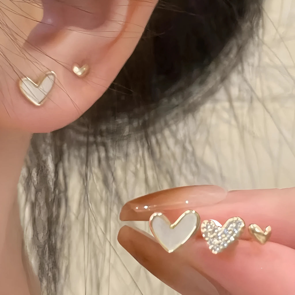Three pairs of heart-shaped alloy earrings with electroplated finish in gold, black, pink or black and white
