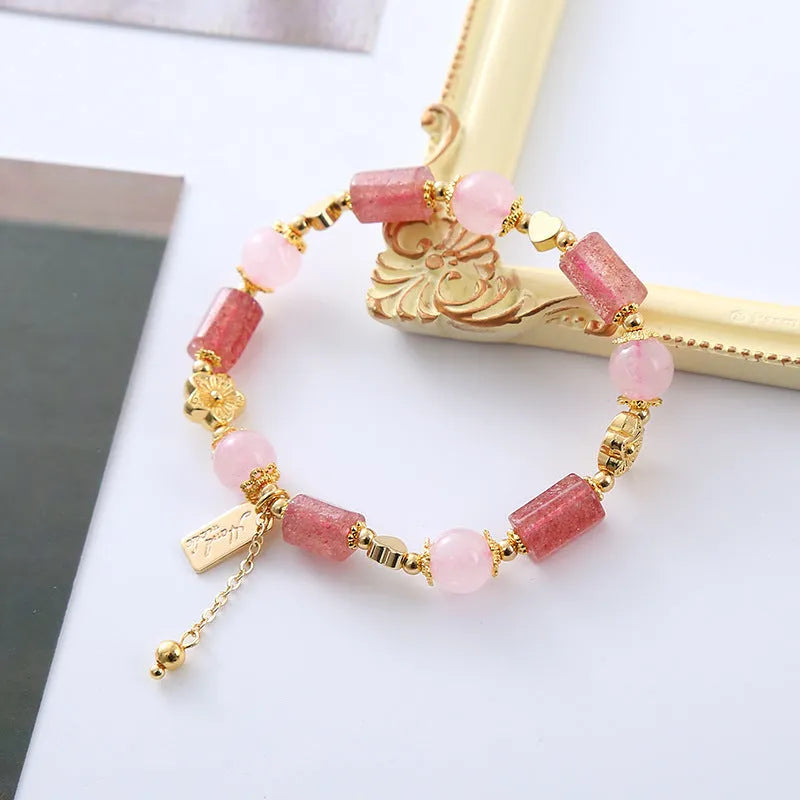 Pink strawberry crystal bracelet with star-shaped beads and a small heart charm on a white background