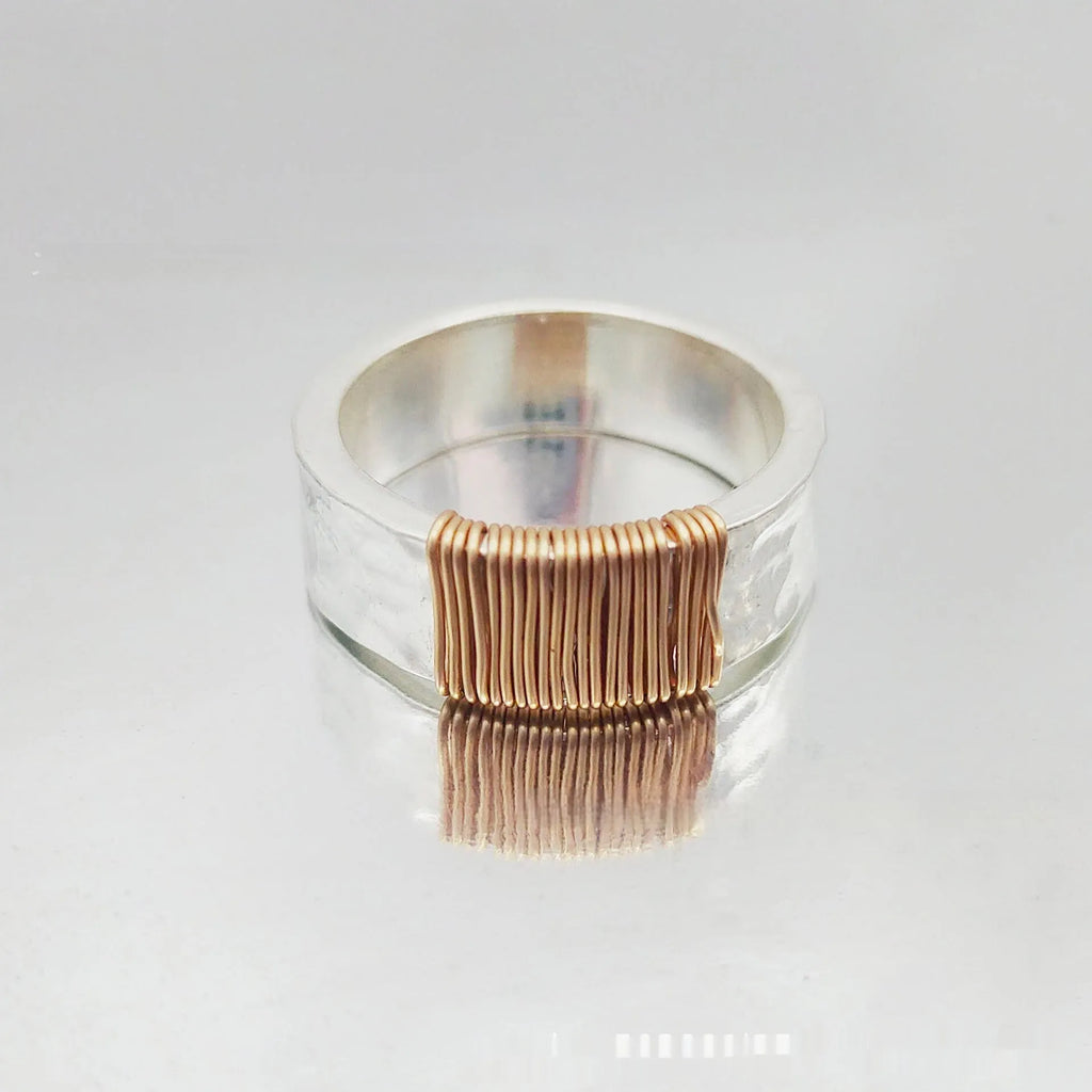 Copper wide face geometric ring bracelet in silver gold coil colour on a plain background.