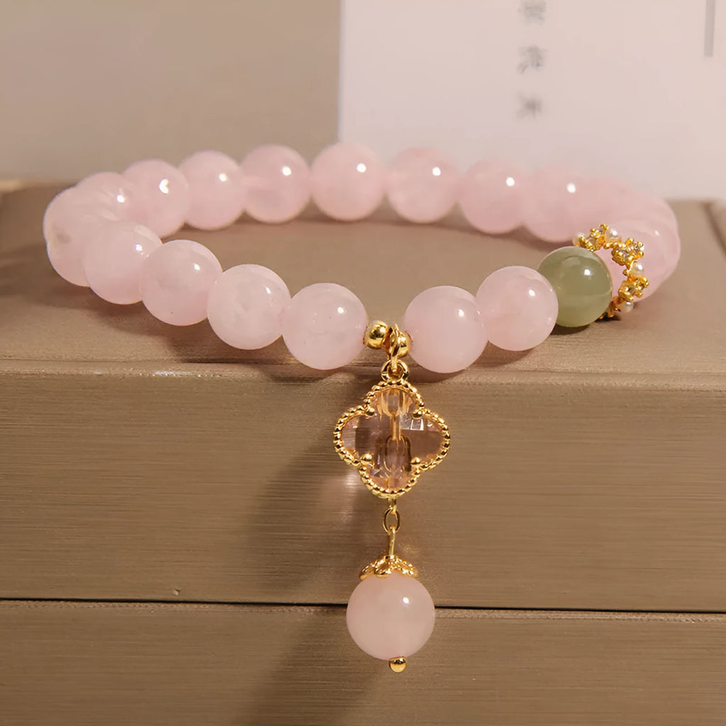 Pink crystal bracelet with a four-leaf clover pendant and rhinestone details on an alloy chain.