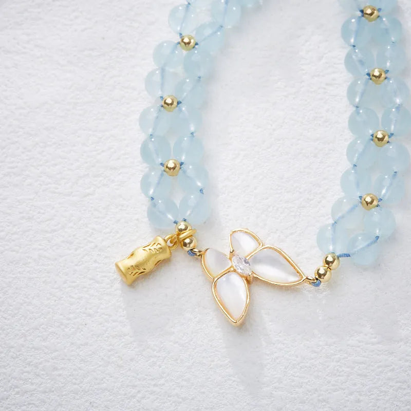 Women's woven bracelet with 6mm aquamarine beads and butterfly design on a wrist.