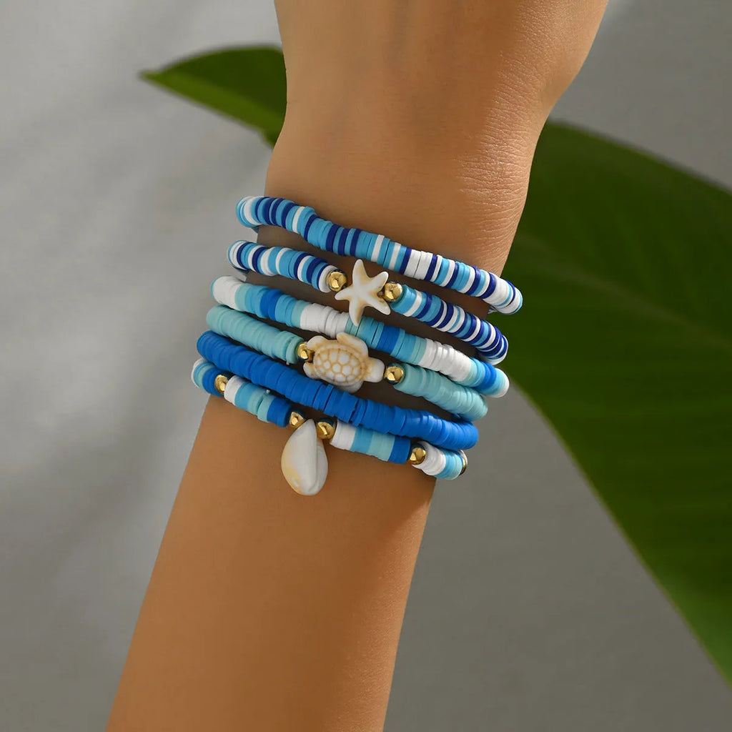 Set of six handmade geometric shell bracelets in Bohemian blue polymer clay.