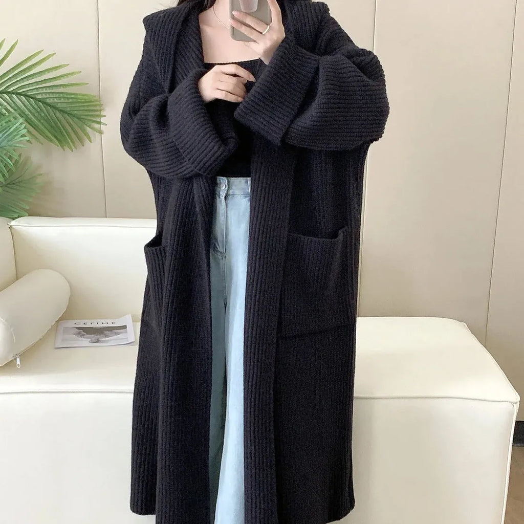 Woman wearing a loose beige hooded zip-front cardigan coat with raglan sleeves.