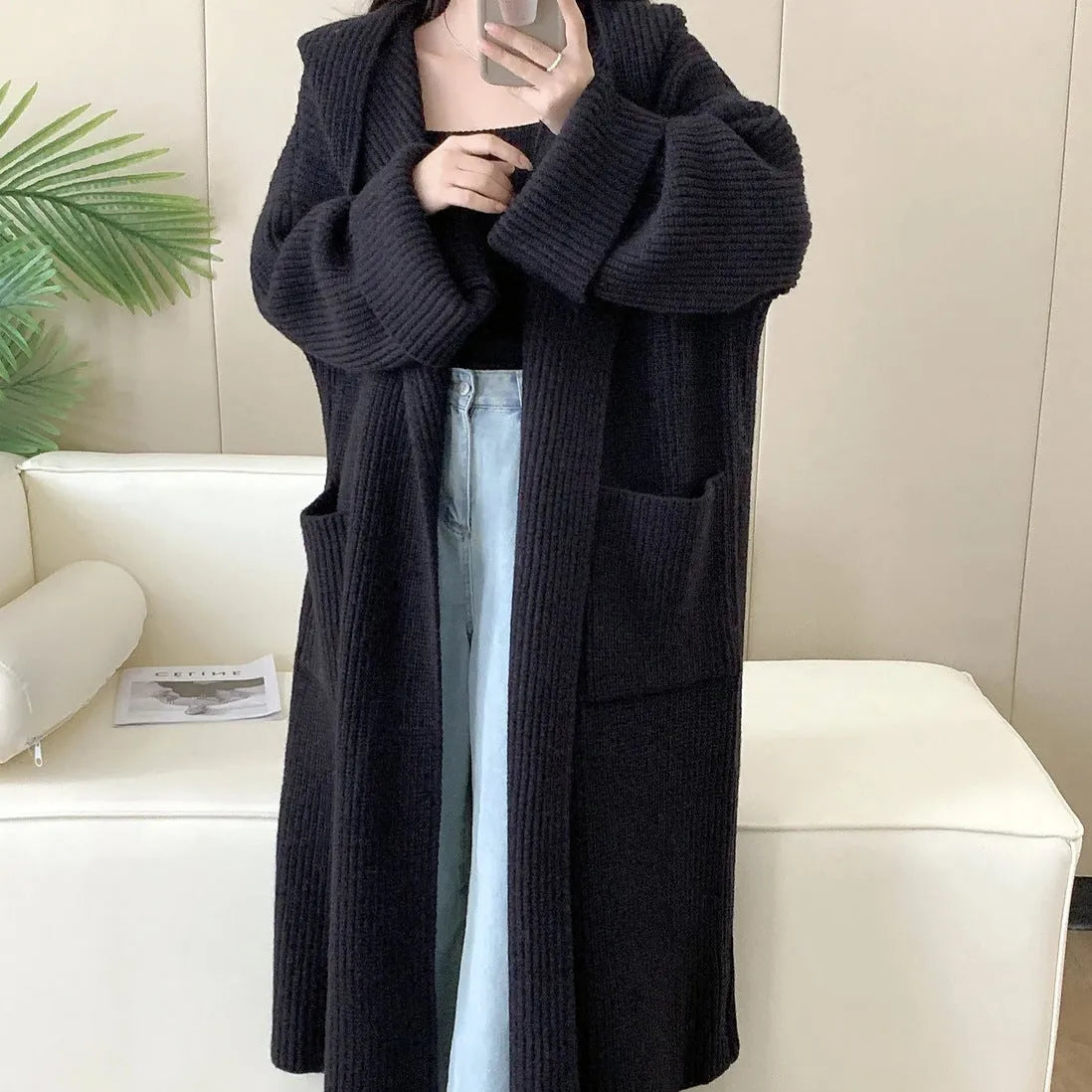 Woman wearing a loose beige hooded zip-front cardigan coat with raglan sleeves.