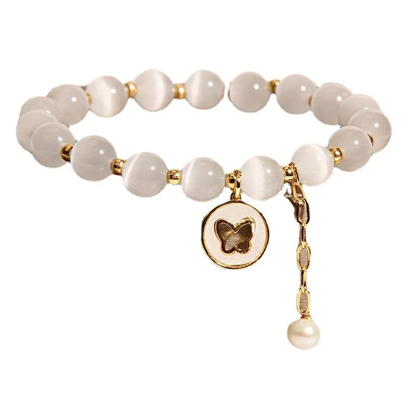 Close-up of a white cat's eye crystal bracelet with geometric links on a wrist.